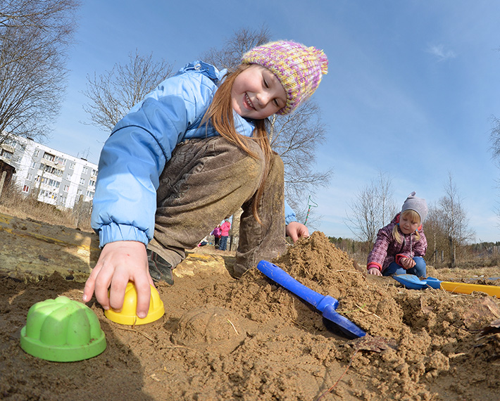 Девочки лепят куличики в песочнице 